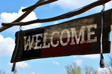 style billboard sign. the board at the top of the gate hangs on ropes. ranch entry to yard. Apache museum in nature. tassels